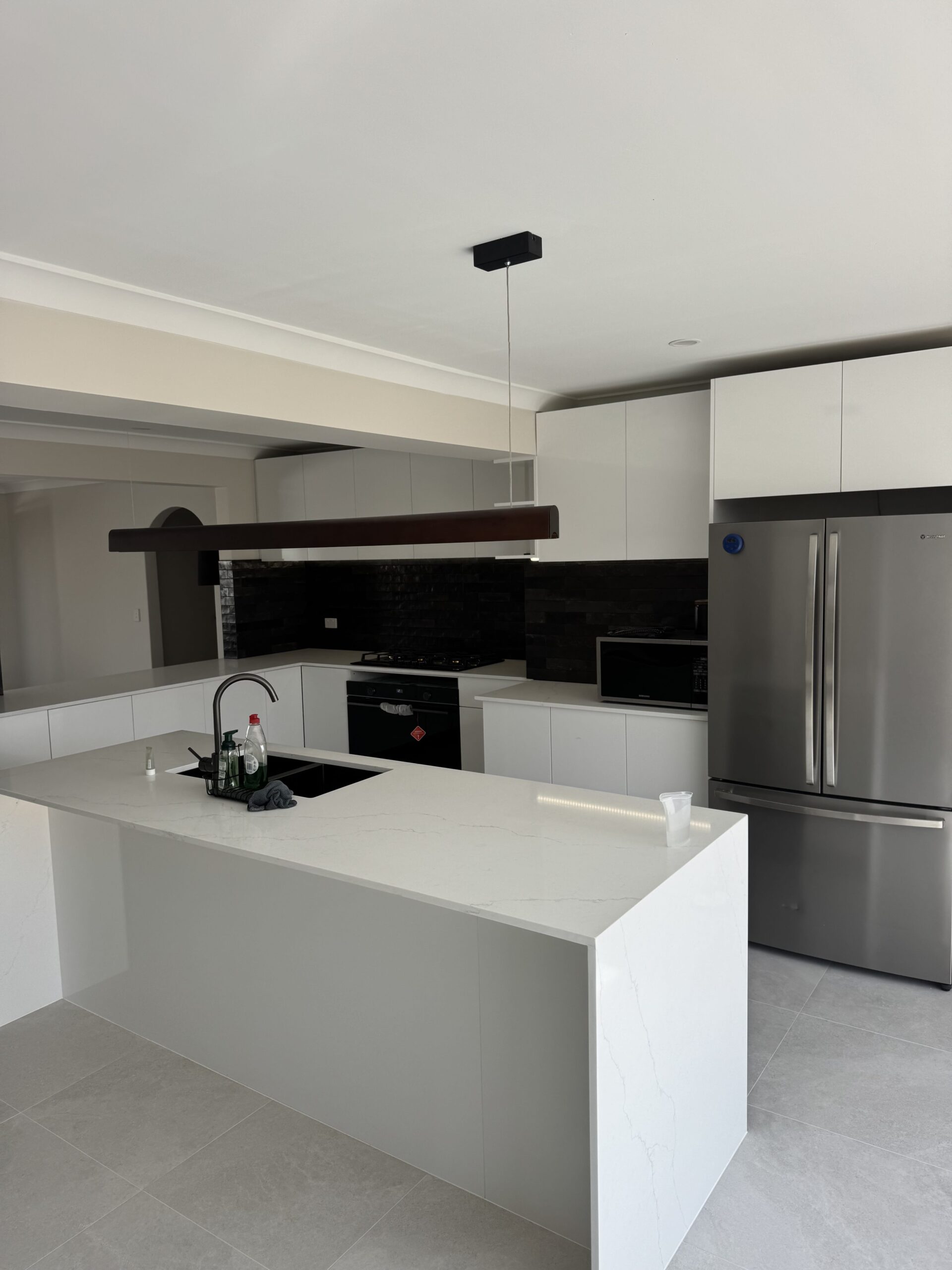 Modern kitchen pendant light installation above island bench